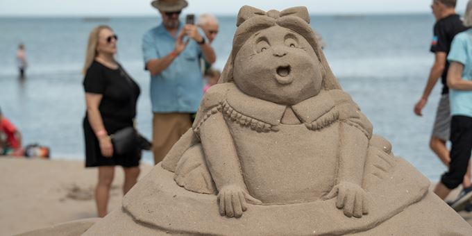 Sand sculpture in front of people taking a photo