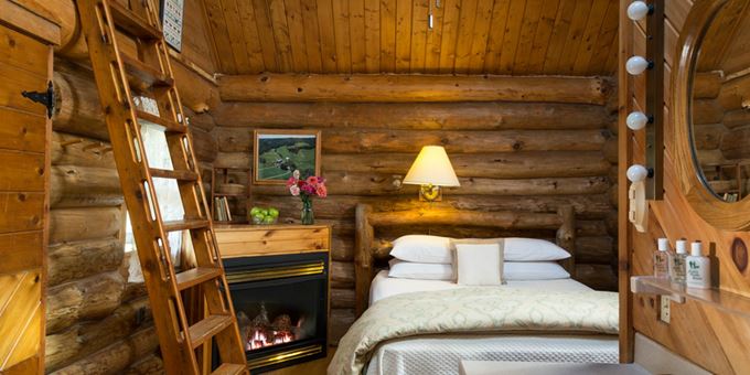 Queen-size bed, fireplace and ladder up to the loft inside the Little House on the Prairie log cabin at Justin Trails Resort.