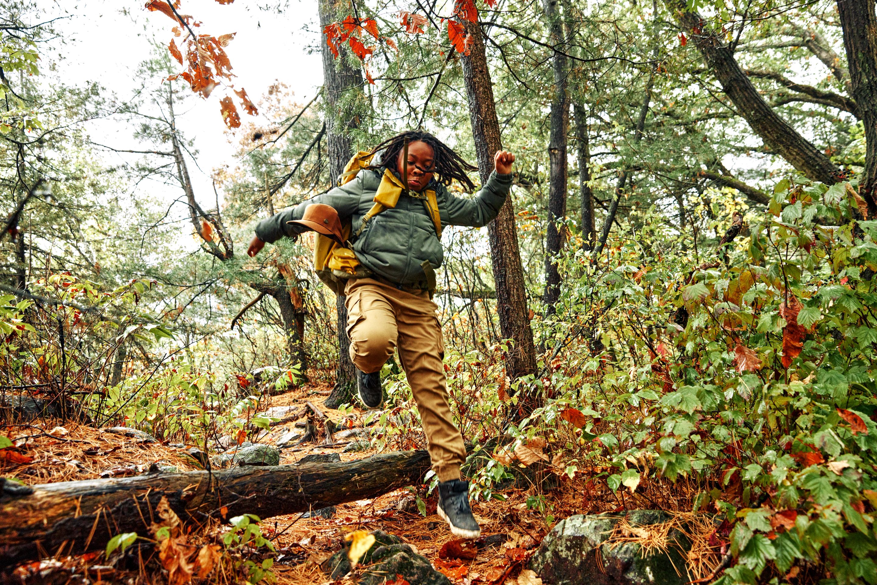 Boy Jumps Over A Log While Hiking At Devil's Lake State Park In Baraboo