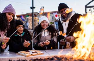 34ab3a5e-c12f-4d30-bf41-9e24d64926ce-145-family-make-smores-at-an-outdoor-fire-at-the-plaza-at-gateway-park-in-neenah