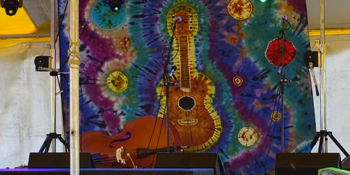 Guitar hanging in front of colored spiral graphic.