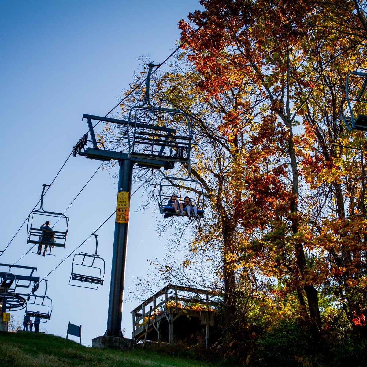 People riding a ski lift around the fall trees