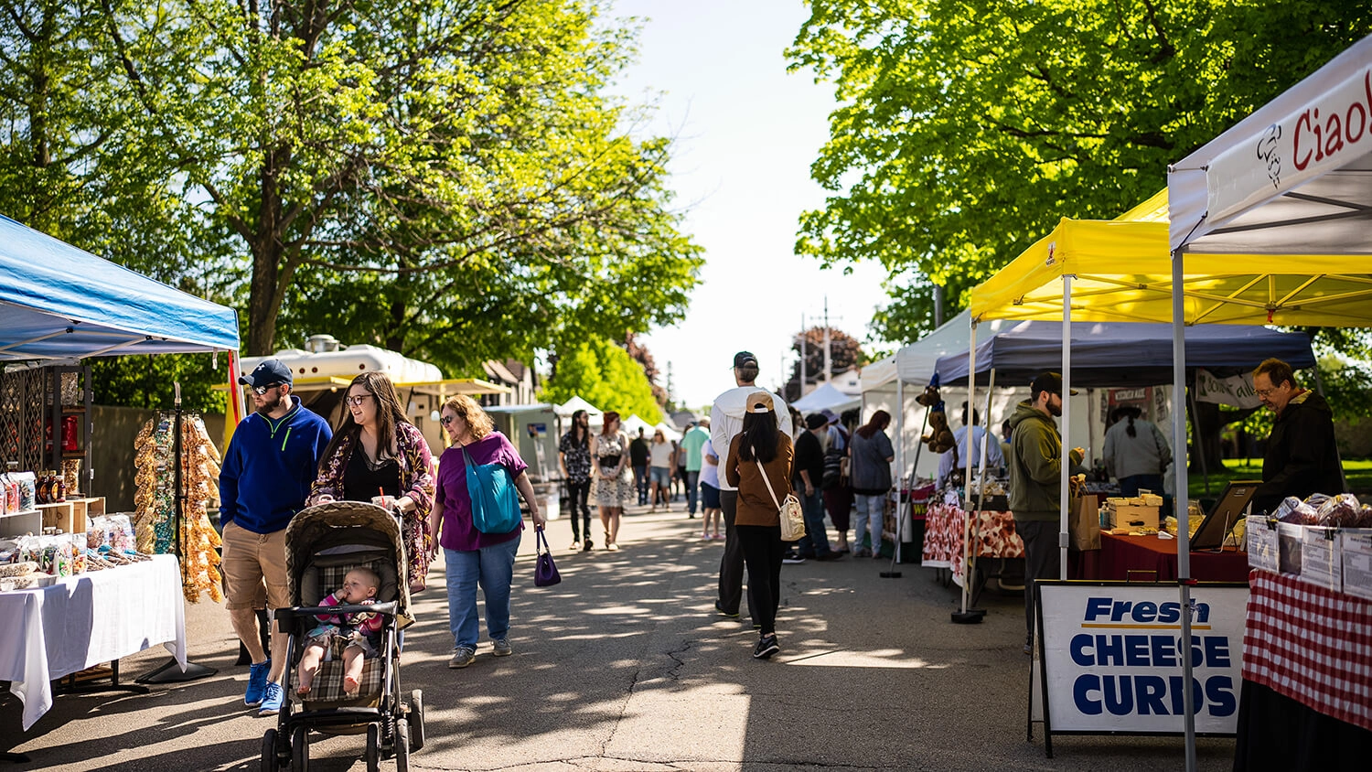 Festival of Spring with stalls selling various goods and people walking, including a couple pushing a stroller.