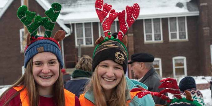 Two teenage girls having fun with reindeer horns on their heads.