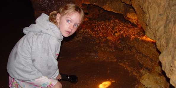 Little girl with flashlight exploring the cave