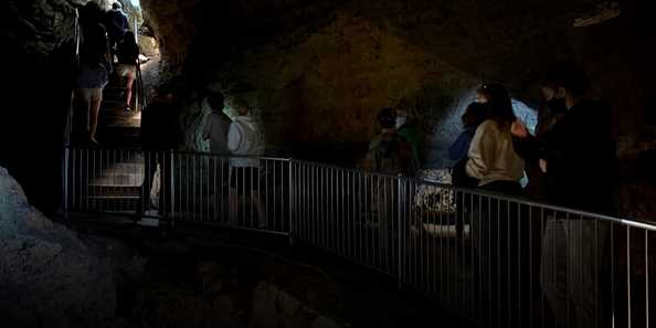 People touring a cave with little to no lights on