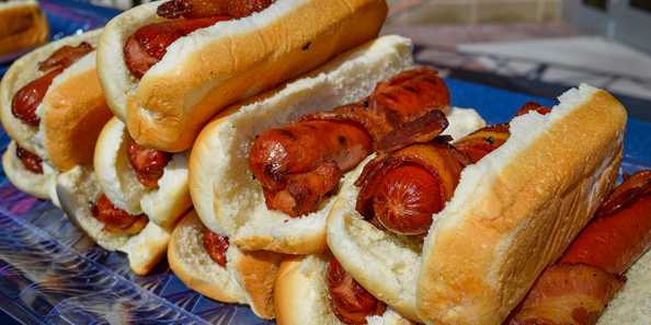 Contenders of the 2019 Adult Eating Contest compete to see who can eat ten of these bacon-wrapped hot dogs first.
