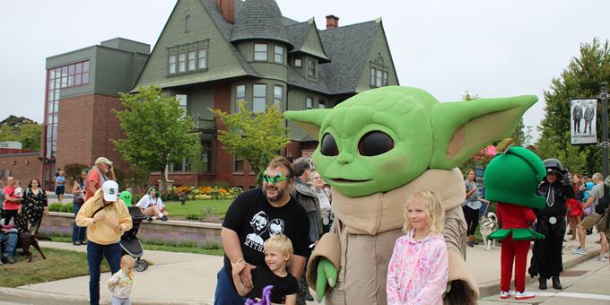 Father and children pose with green character