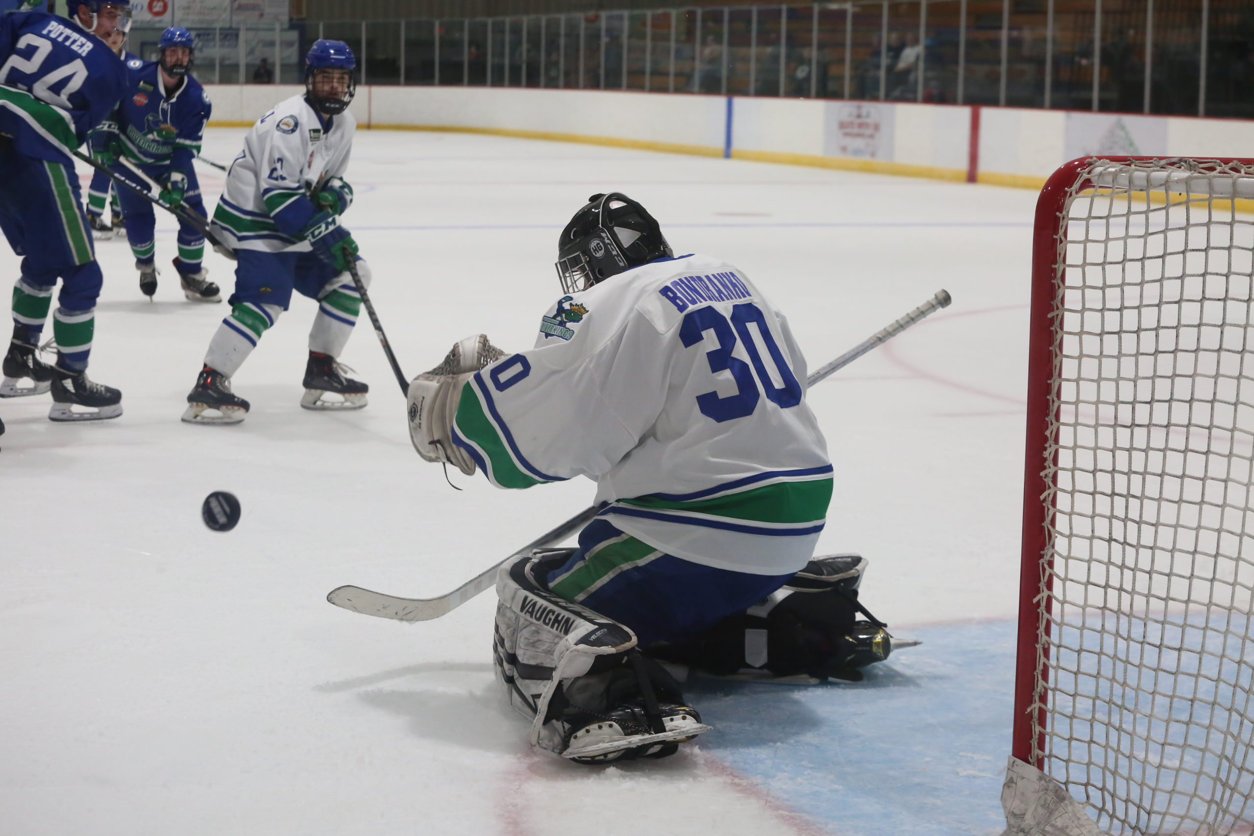 Ice hockey goalie making a save to prevent goal.