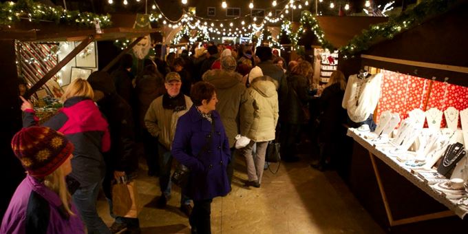 Vendors line the outdoor Christmas Village under a canopy of lights.