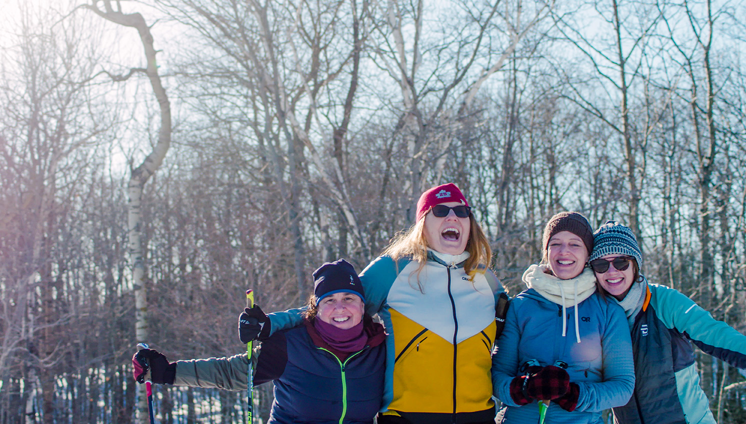 Friends huddled together in front of cliffs covered in snow and icicles