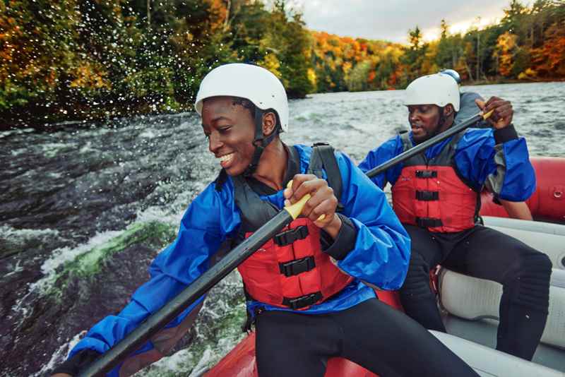 close up of a family paddling and going down rapids in a raft