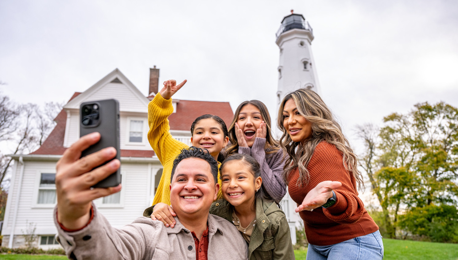 family taking selfie with milwaukee's north point lighthouse in the background