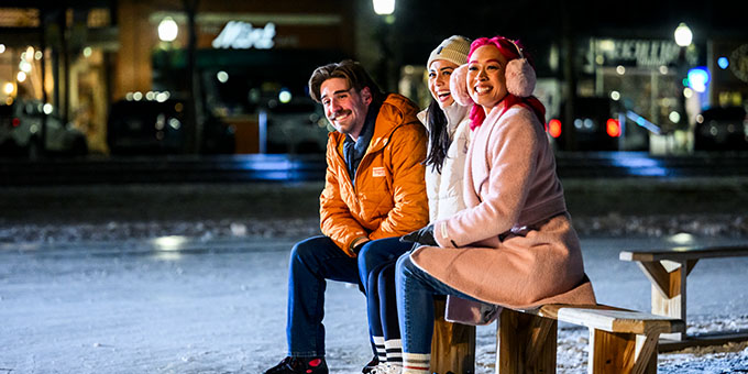 Friends laughing and sitting on a bench outside