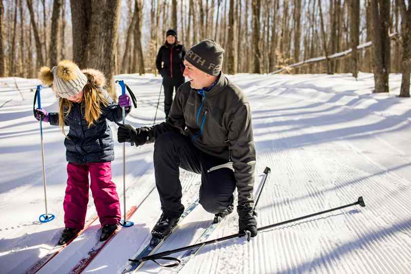 Father helping child cross-county ski