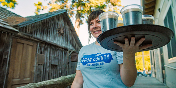 Server wearing a Door County Brewing Co. t-shirt carrying a round tray of drinks