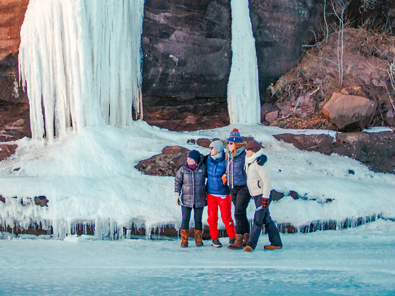 friends standing for a picture on the ice in bayfield