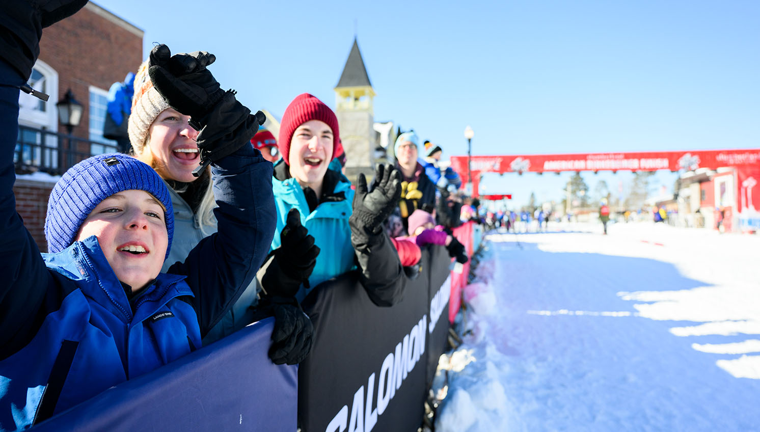 family cheering for birkie ski racers near the finish line