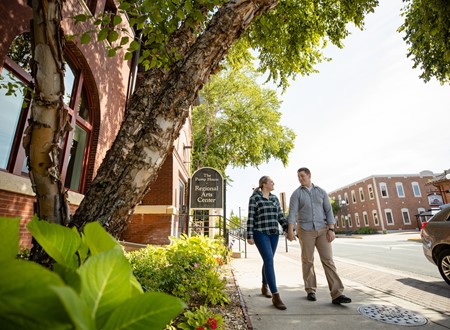 couple walking holding hands while shopping loading=