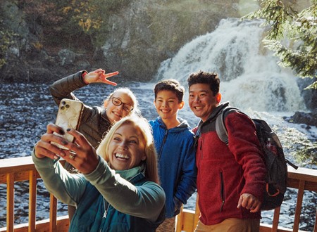 family taking a selfie in front of a waterfall loading=