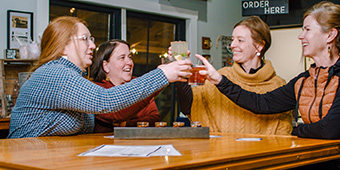 Friends cheers drinks at a wooden table
