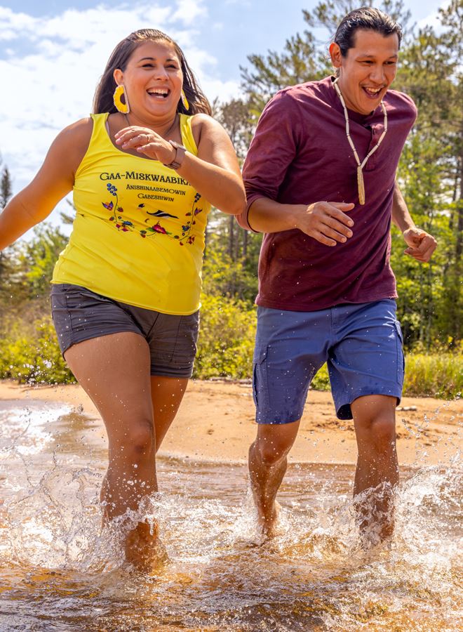 couple running through the water on a beach