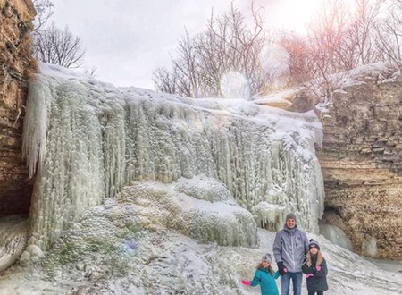 family standing in front of frozen waterfall loading=