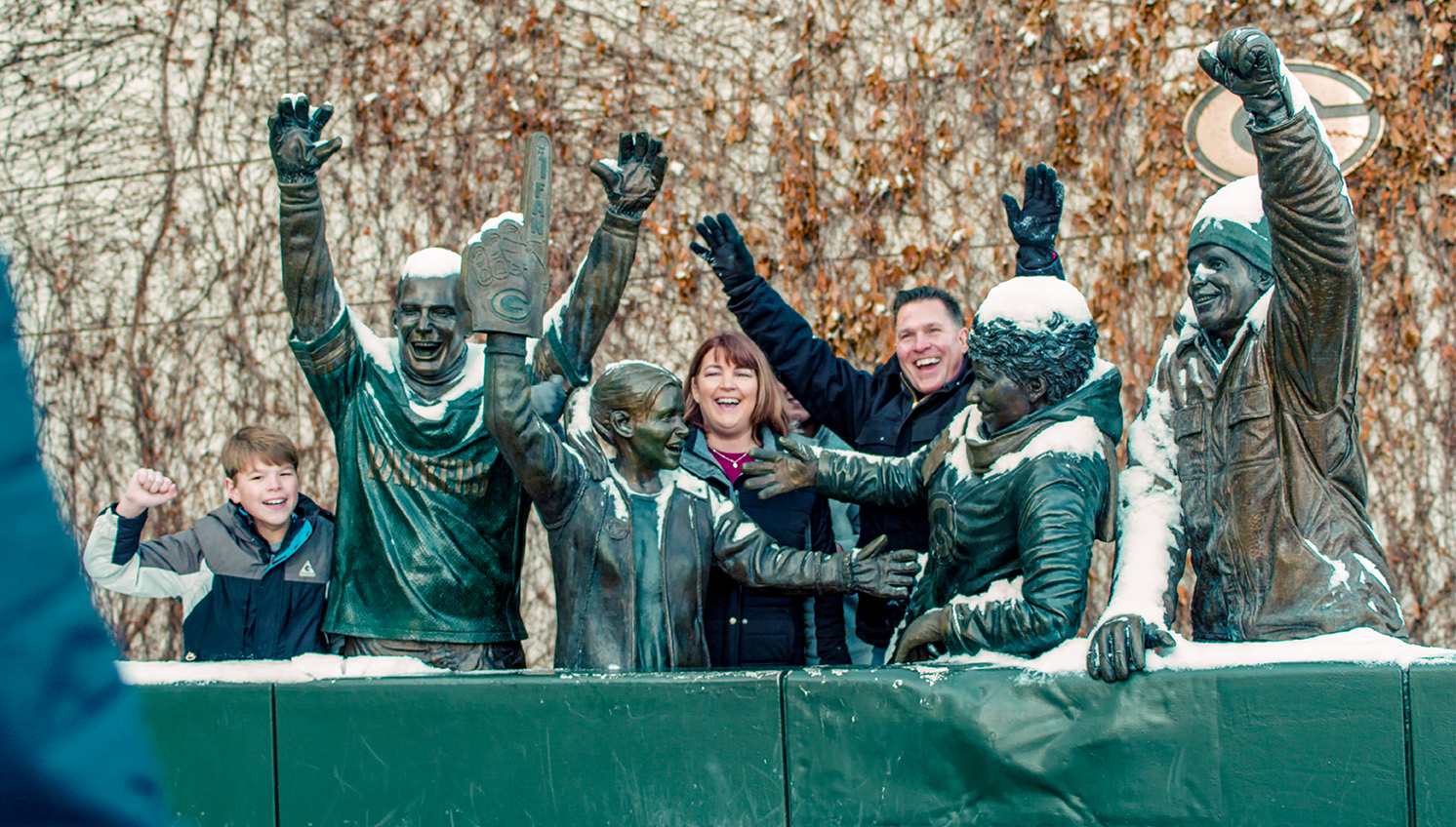 family posing around packers fan statues