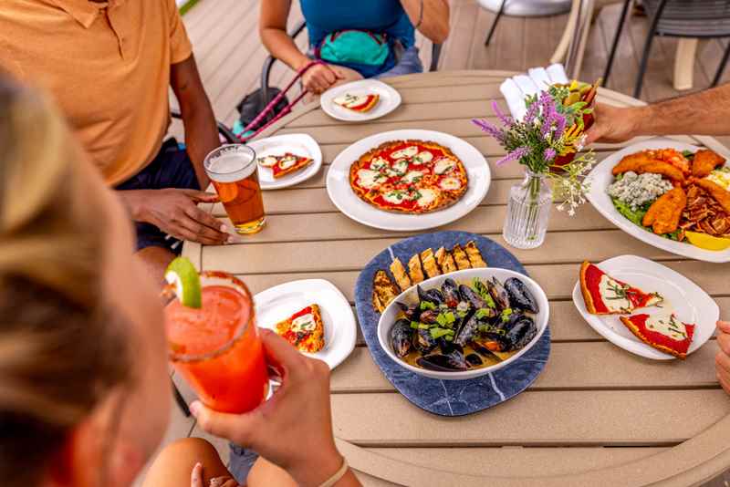 Plates of pizza and seafood on an outdoor table decorate with a jar of flowers