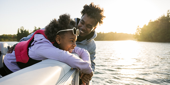 father and daughter smiling and enjoying a pontoon ride