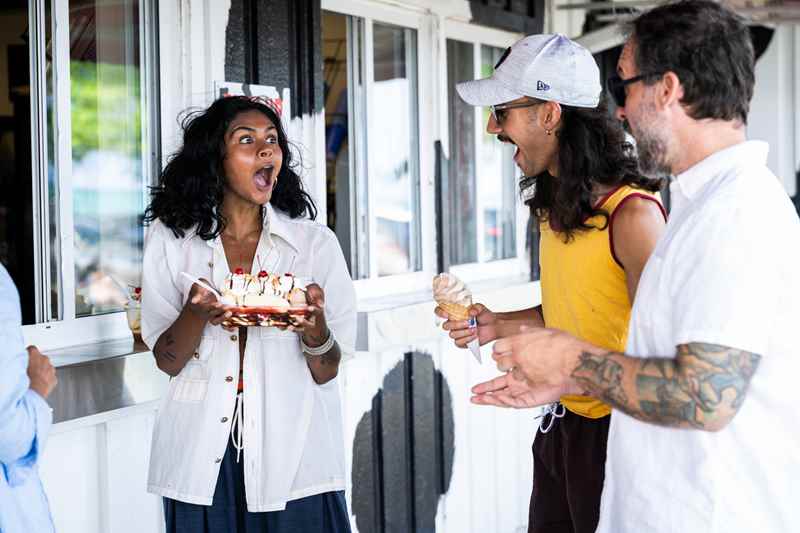 3 people look surprised while one woman holds a giant banana split