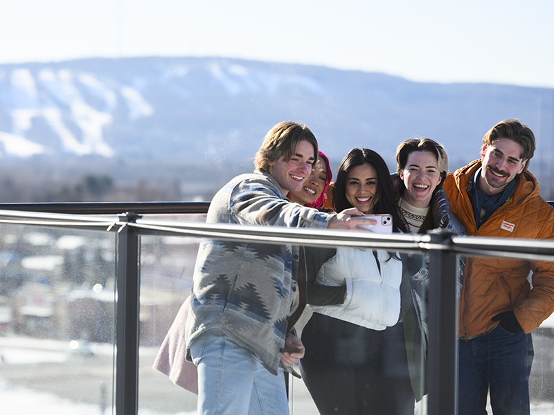Friends taking a selfie at a lookout point with a mountain or hill in the background