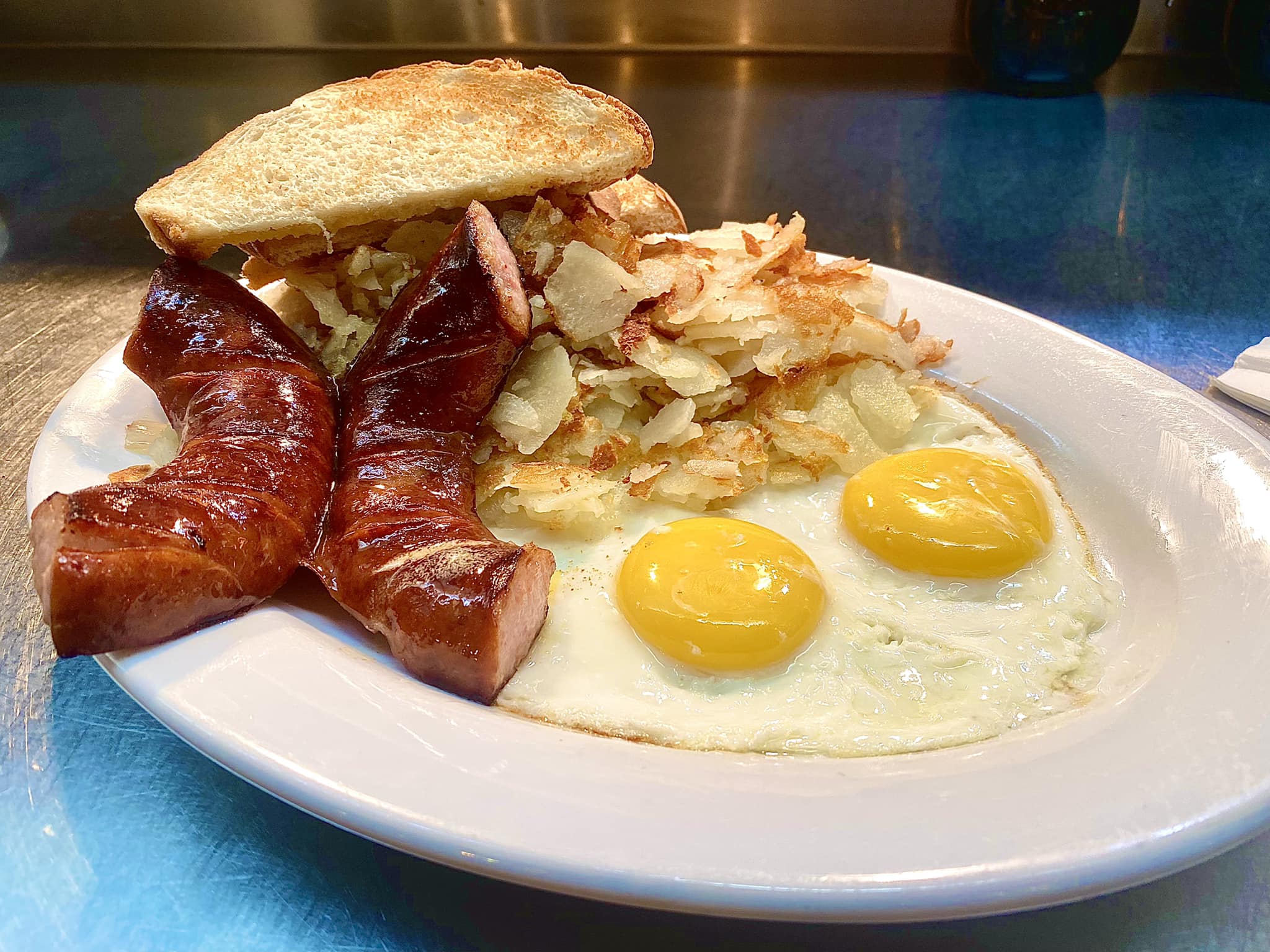 A hearty breakfast plate featuring sunny-side-up eggs, crispy hash browns, toast, and juicy kielbasa sausage—just one of the many homestyle meals served at Truck’s Place Family Restaurant.