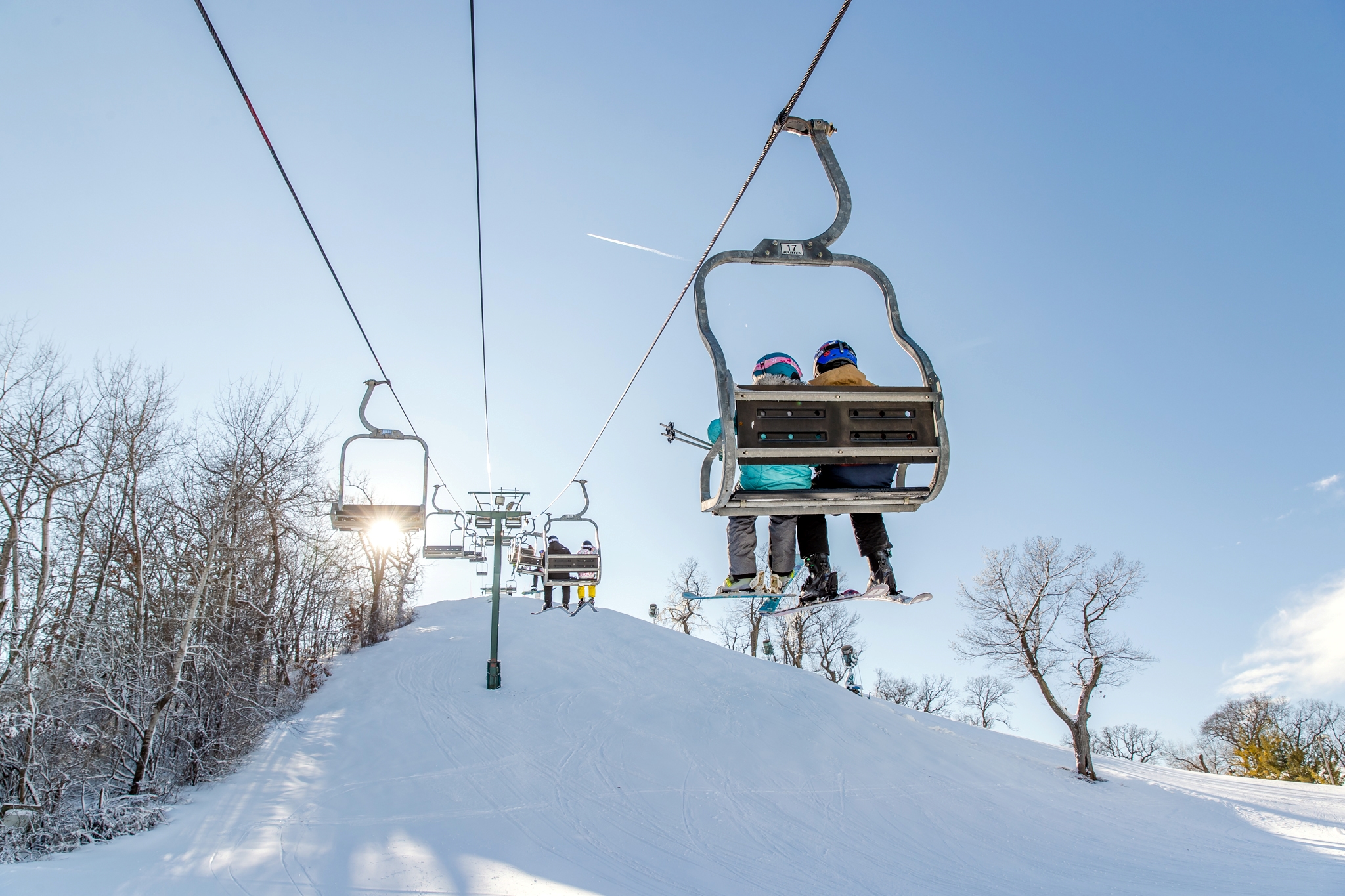 Skiers on the chairlift in the sun
