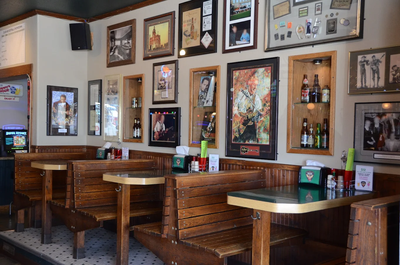 Interior of a restaurant with wooden booths and framed artwork on the walls.
