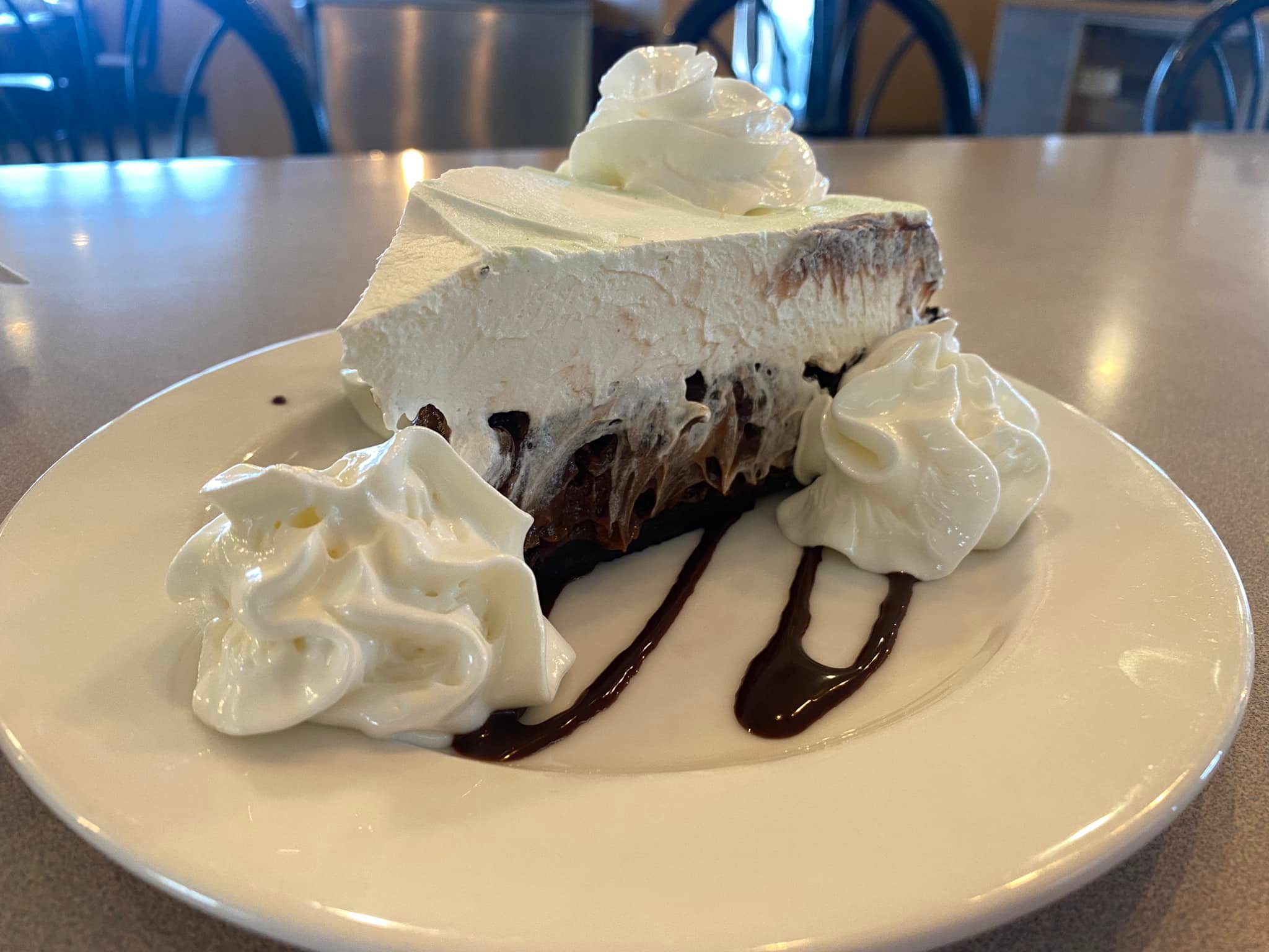 A decadent slice of chocolate cream pie topped with whipped cream and a drizzle of chocolate sauce—perfectly sweet ending to any meal at Truck’s Place.