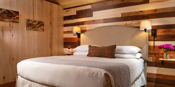 King-size bed inside bedroom with walnut, cherry, spalted maple, oak and basswood on the walls inside the Sunrise Cottage at Justin Trails Resort