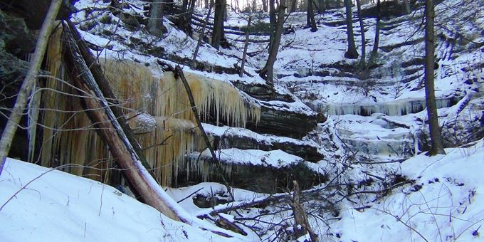 Frozen waterfall with logs among the icicles