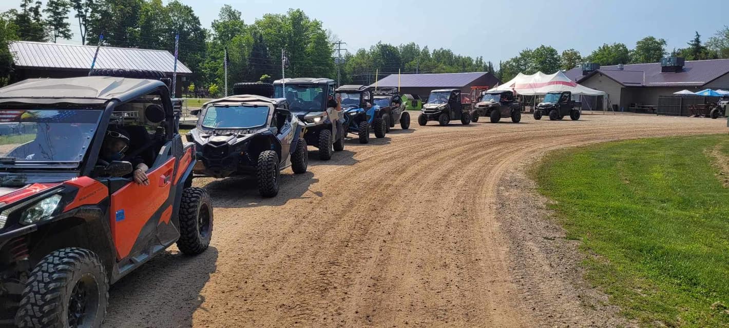 A group of UTV riders heads out from a local business along the Pickerel/Pearson ATV Trail, ready to continue their adventure through the scenic landscapes of Langlade County.