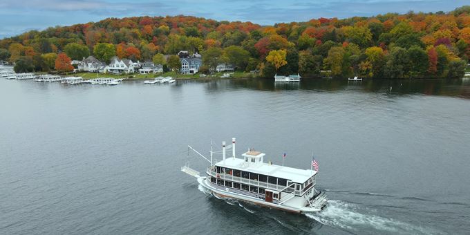 Aerial shot of a boat cruising the lake in the fall