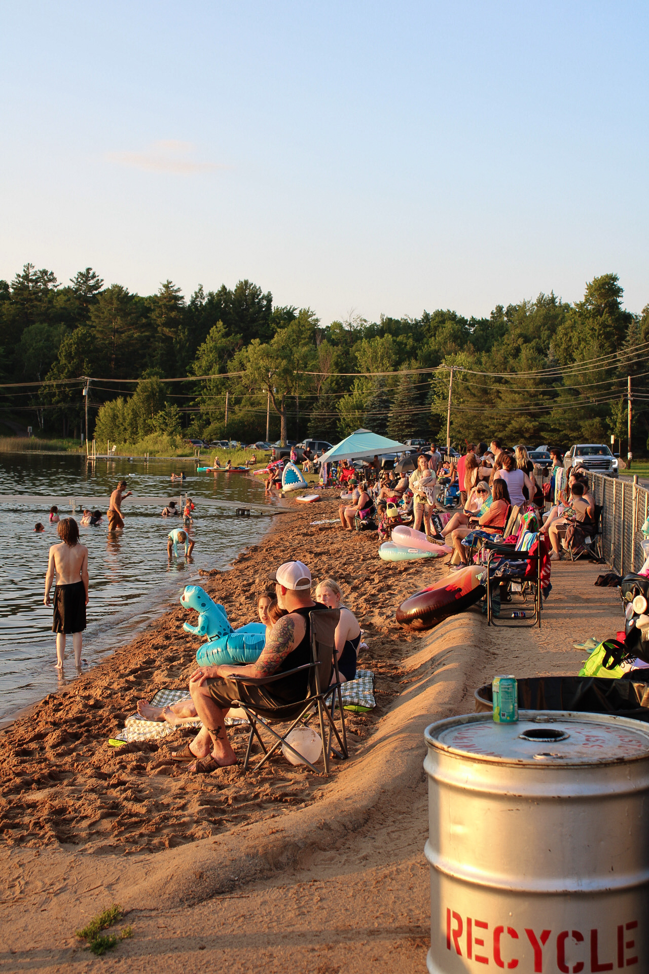 Visitors relax and play along the sandy shore of White Lake Beach, soaking up the sun and enjoying the refreshing waters.