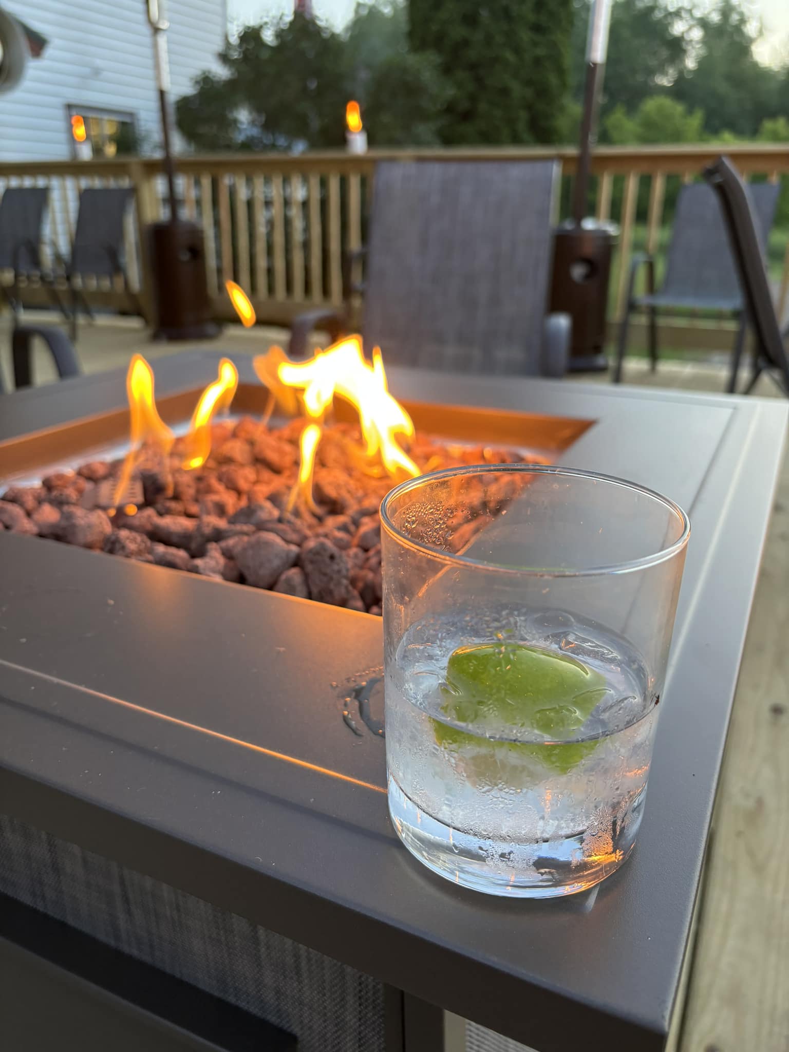 A refreshing cocktail rests beside a glowing fire table on the Foxwood Tavern patio—inviting guests to unwind with a drink and good company in a cozy outdoor setting.