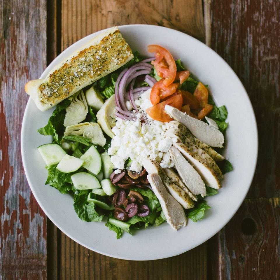 Greek salad - A heathy mix of greens, red onions, tomatoes, cucumbers, kalamata olives, feta, artichoke hearts, &amp; fresh basil pesto; served with Greek vinaigrette dressing &amp; made-from-scratch Christianos bread. We also added chicken here for extra protein!