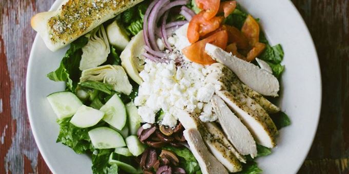 Greek salad - A heathy mix of greens, red onions, tomatoes, cucumbers, kalamata olives, feta, artichoke hearts, &amp; fresh basil pesto; served with Greek vinaigrette dressing &amp; made-from-scratch Christianos bread. We also added chicken here for extra protein!