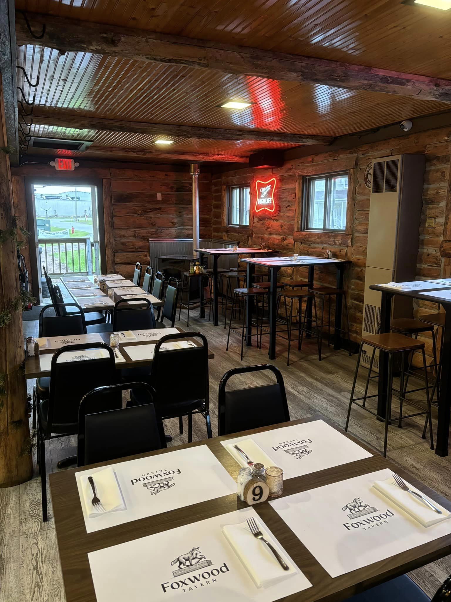 Inside Foxwood Tavern, rustic log walls and warm lighting create a welcoming cabin feel. Tables are set and ready for guests to enjoy hearty meals in this charming Northwoods dining spot.