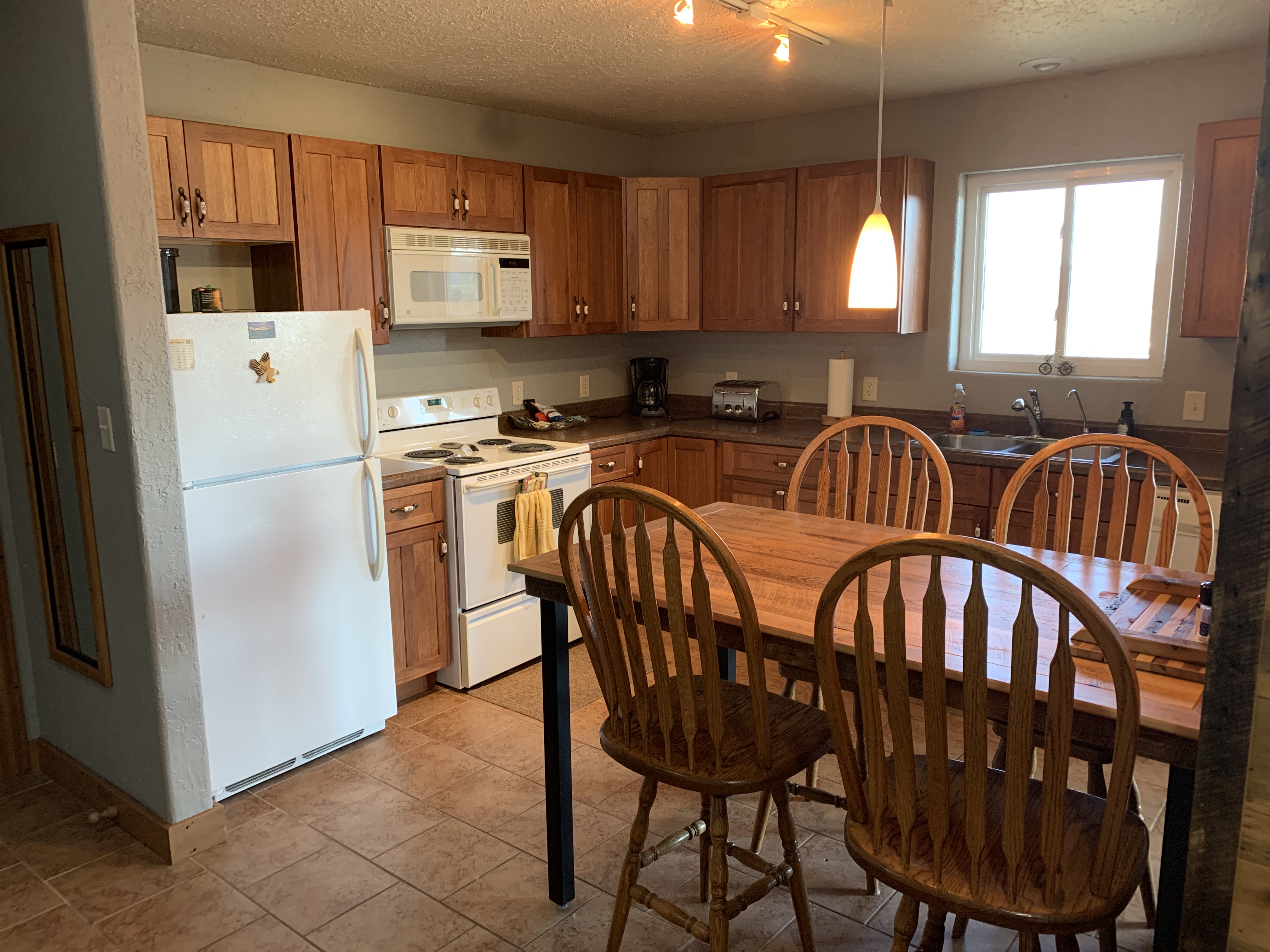 Kitchen with full size appliances is stocked with pots, pans, utensils and table service.