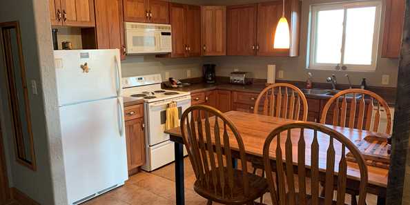 Kitchen with full size appliances is stocked with pots, pans, utensils and table service.