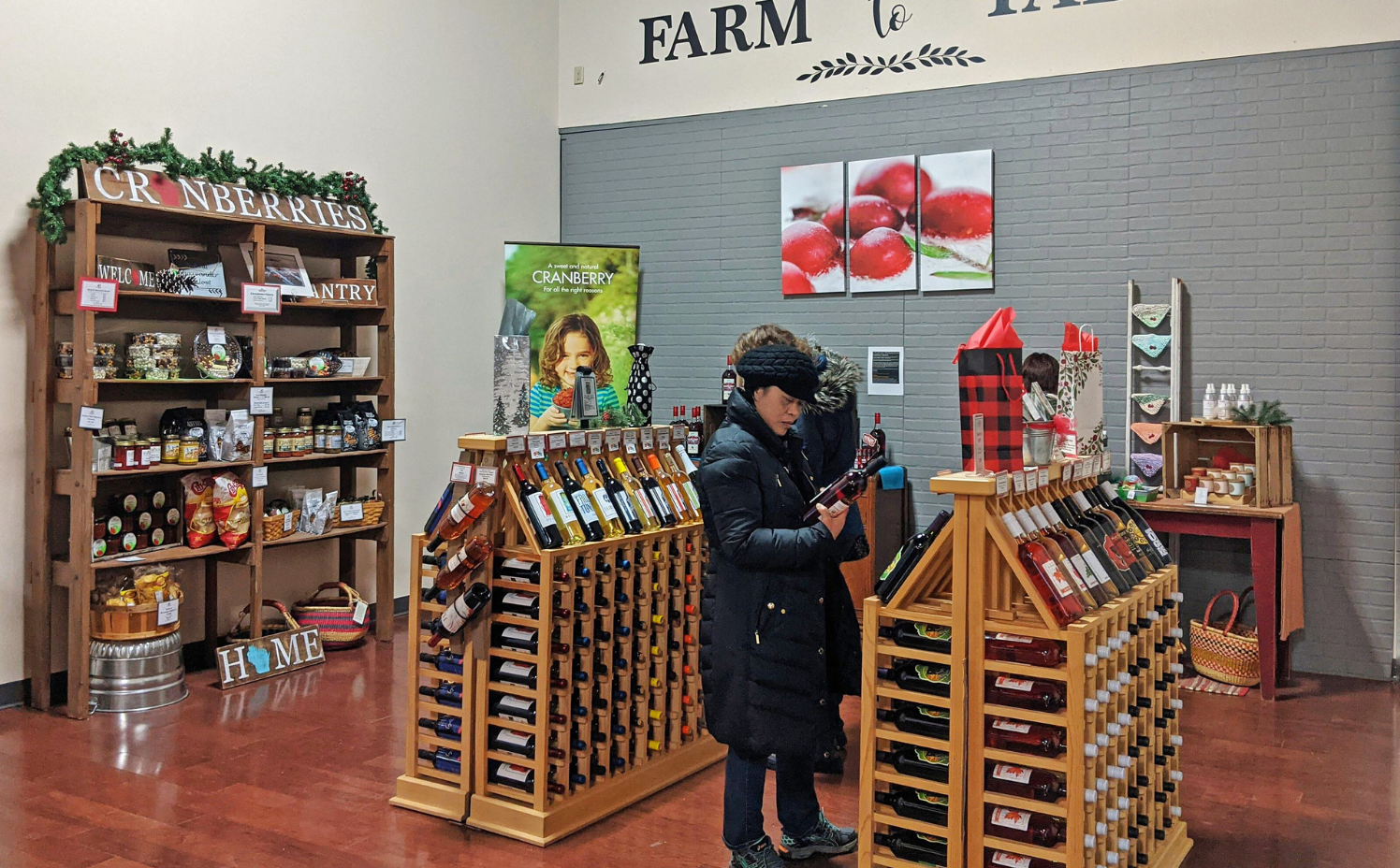 Woman shopping by rack of wine and food.